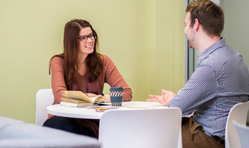 Two students talking at table