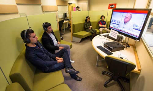 Students watching screen in media facility.