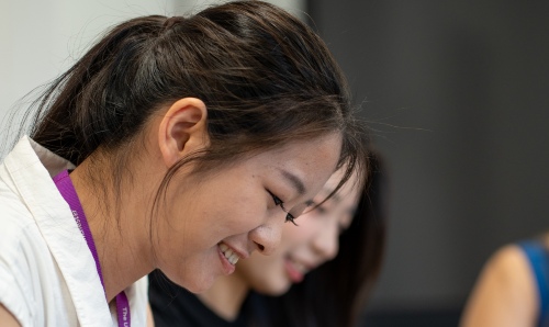 Female student looking down and smiling as she works.