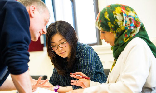 Three colleagues engaged in a discussion at a table.