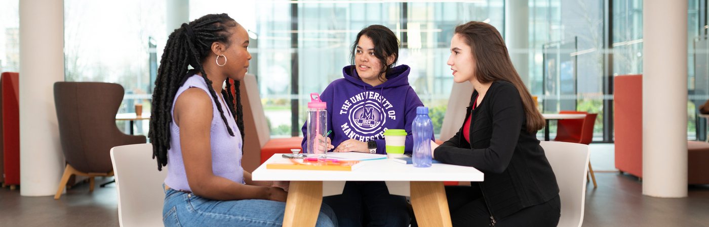 Three students sat together making notes